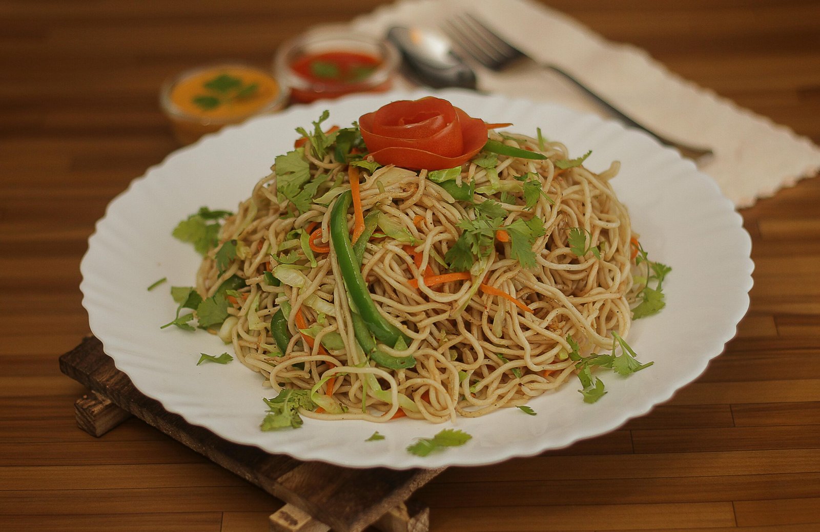 A plate of delicious Nepali chow mein garnished with fresh vegetables and herbs, perfect for lunch or dinner.