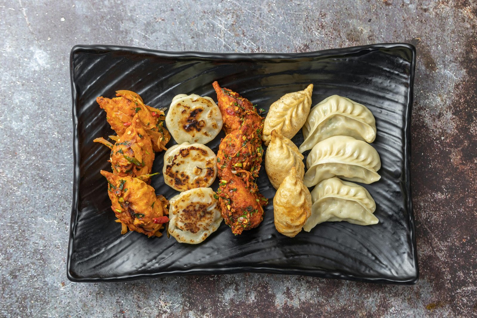 A delicious assortment of fried and steamed dumplings on a stylish plate, ready to eat.